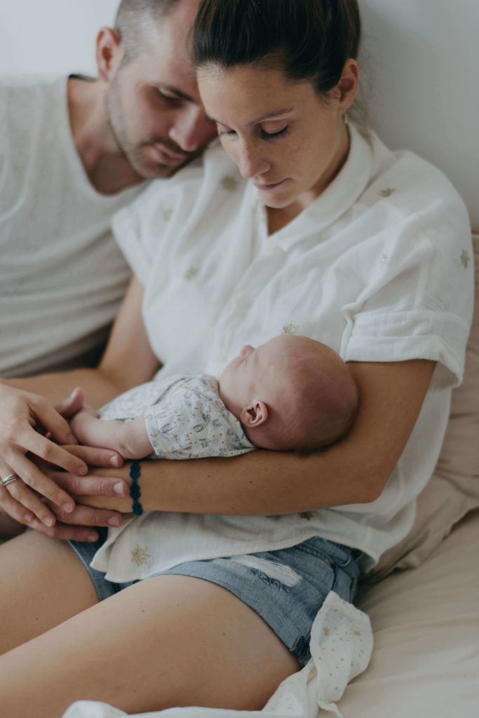 Bébé dans les bras de maman avec papa à coté