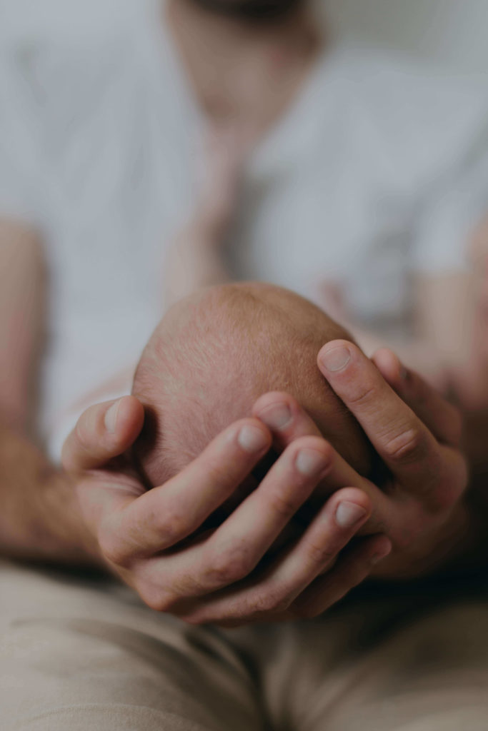 Main de papa autour de la tête du nouveau né