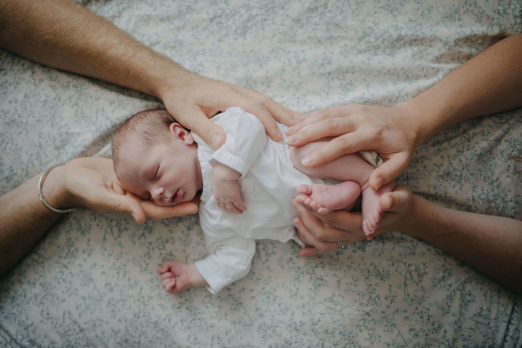 nourrisson tenu par les mains de ses parents